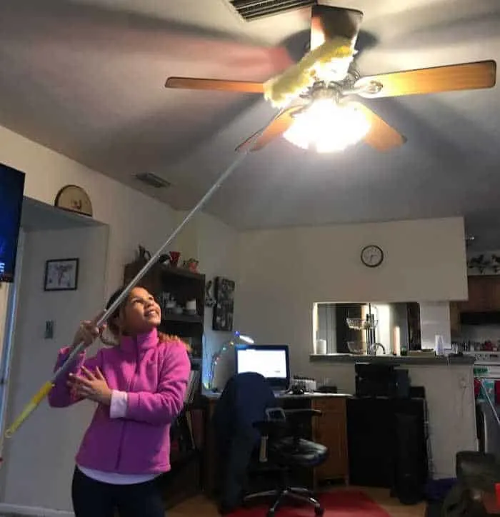girl dusting ceiling fan with Swiffer duster