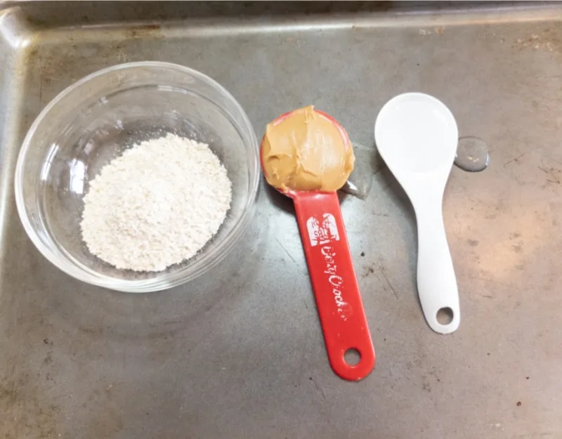 bowl of oats, spoon of peanut butter and spoon of water