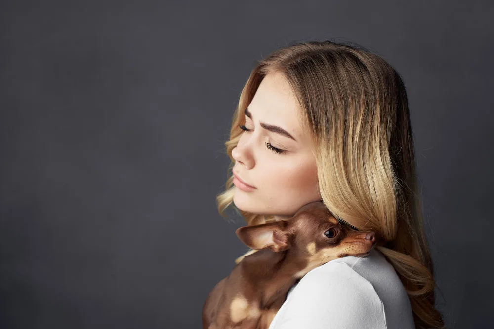 young blond woman snuggling chocolate chihuahua