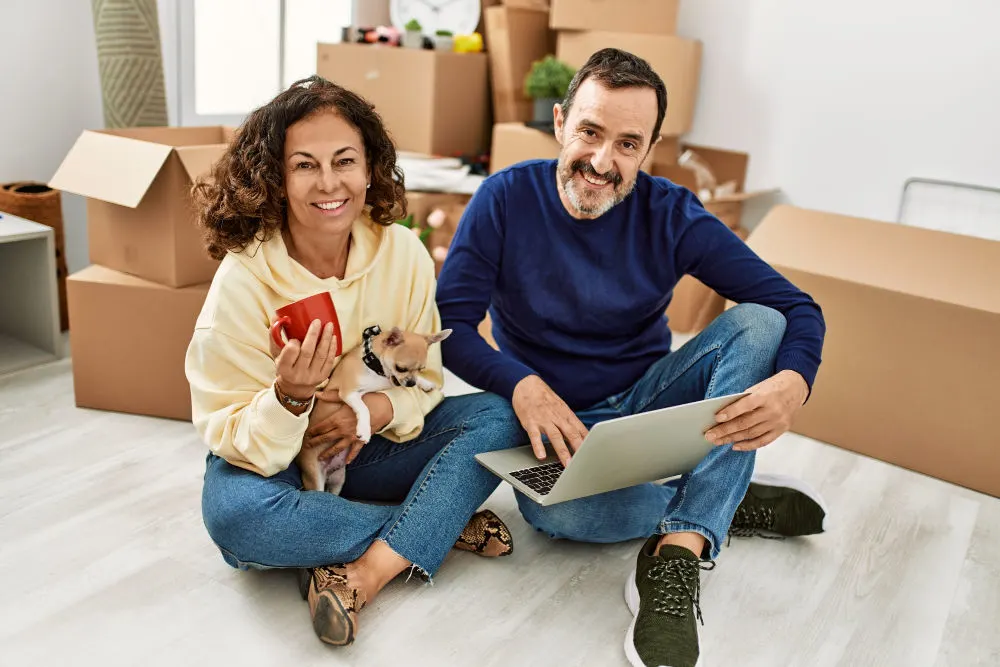 man and woman with chihuahua and cardboard moving boxes